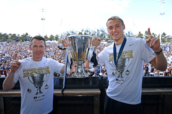 Collingwood coach Craig McRae and skipper Darcy Moore hold up the 2023 premiership cup.