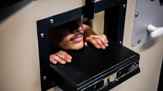 A Silverwater Correctional Centre prisoner peers out of the meal slot in his cell door. 
