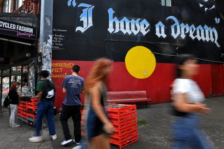 People walk past a mural of the Aboriginal flag in Newtown.