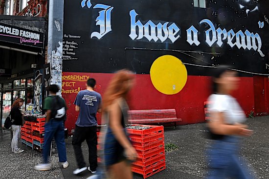 People walk past a mural of the Aboriginal flag in Newtown.