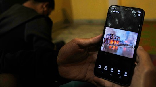 A Myanmar refugee who fled the violence watches photos of it on their phone in India.