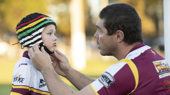 Father Sean Buchanan adjusts the headgear on his six-year-old son Beau, who plays for the Glenmore Park Brumbies in the Penrith Junior Rugby League.