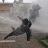Protesters are hit by a police water cannon during clashes at a march marking the 50th anniversary of a military coup led by General Augusto Pinochet, in Santiago, Chile.