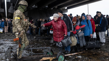 Residents of Irpin flee heavy fighting via a destroyed bridge as Russian forces enter the city.