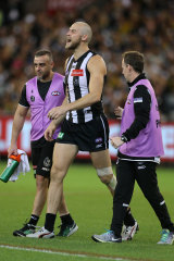 Over and out: Ben Reid is escorted from the ground by trainers are suffering an injury in the round six clash against the Tigers.