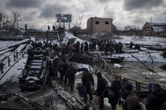 烏克蘭人在逃離伊爾平時穿過一座被毀壞的橋下的臨時小路。