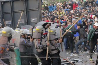 Student protesters throw projectiles at riot police outside the parliament building in Jakarta, Indonesia, on Tuesday.