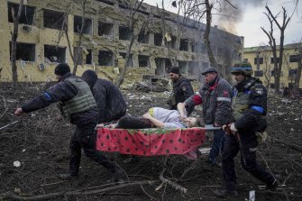 Emergency workers and volunteers carry a wounded pregnant woman from a maternity hospital in Mariupol after it was hit in a Russian air strike.