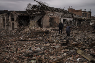 Sakinler, Trostsyanets kasabasında yıkılan binaların molozları üzerinde yürüyor.