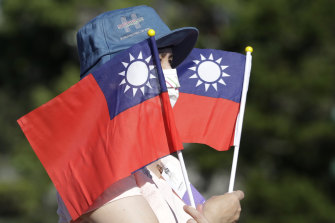 A woman holds up Taiwan national flags during National Day celebrations in front of the Presidential Building in Taipei, Taiwan. 
