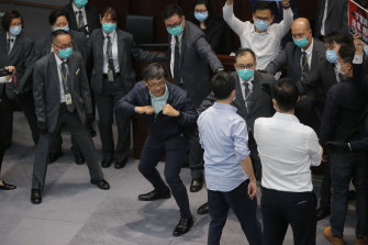 Pro-China legislator Junius Ho, centre, gestures as he attempts to scuffle with pro-democracy legislators at the Legislative Council's House Committee meeting, in Hong Kong.