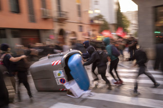 Pro-independence demonstrators push over rubbish skips to block the street during a protest in Girona on Tuesday.