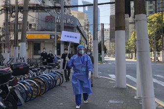 A worker in protective gear holds a sign which reads “Do not crowd” during a mass testing day for residents in a lockdown area in the Jingan district of western Shanghai.