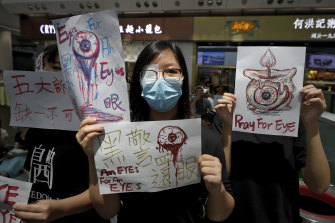 After a girl is hit in the eye with a police beanbag round, protesters wear patches in solidarity as they occupy the city's airport in August.