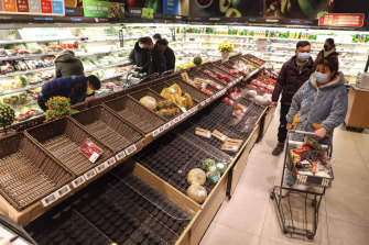 Shoppers look for groceries at a supermarket in Wuhan in January.