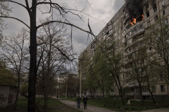 People walk near an apartment on fire after it was hit during a Russian bombardment in Kharkiv.