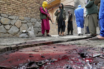 Taliban fighters stand guard on a blood-stained street at the site of an explosion in front of a school in Kabul.