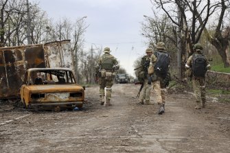 Le milizie repubblicane camminano vicino a veicoli danneggiati durante pesanti combattimenti in un'area controllata dalle forze separatiste sostenute dalla Russia a Mariupol.