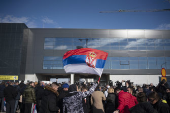 People wave a Serbian national flag outside the VIP exit of Belgrade’s international airport on Monday.