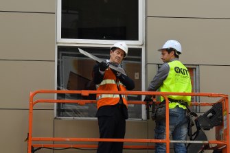 Better Regulation Minister Kevin Anderson, left, inspects a sheet of cladding at the Foundry apartment building in Darlington.