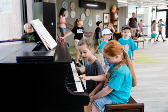 It requires a village: Students play a grand piano during lunchtime in Lindfield Learning Village.