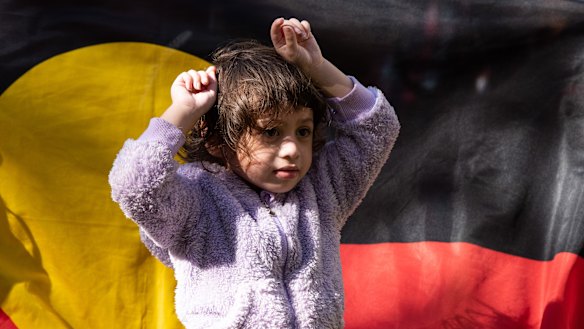 A young girl puts her fists up in the air in a sign of protest. 