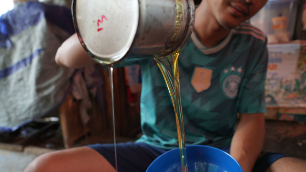 A shopkeeper packages cooking oil at Kambing market in Jakarta.