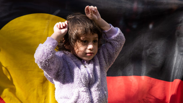 A young girl puts her fists up in the air in a sign of protest. 