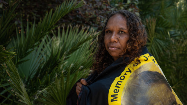 Bernadette Clarke wrapped with an Aboriginal flag with her sister's photo. 