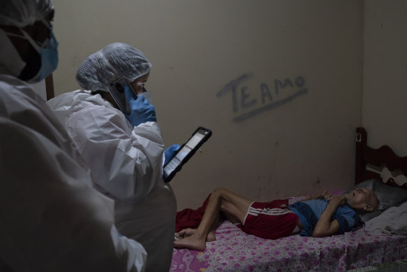 Mobile Emergency Care Service (SAMU) worker Aline Moreira checks on an elderly COVID-19 patient at home before transferring him to a hospital in Duque de Caxias, Rio de Janeiro state, Brazil. On the wall, the message “I love you”.