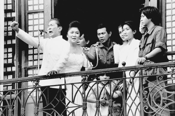 Ferdinand Marcos, with his wife Imelda at his side and Ferdinand Marcos jr, far right, gestures from the balcony of Malacanang Palace on February 25, 1986 in Manila, just after taking the oath of office as president of the Philippines. 