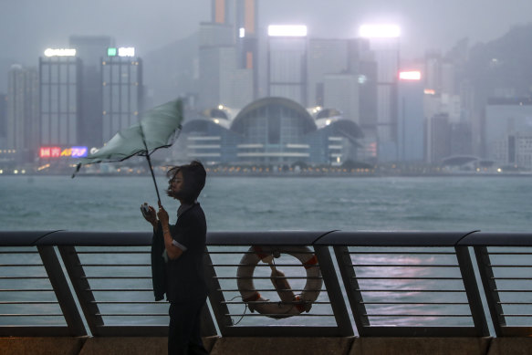 A woman’s umbrella is blown at the seaside as typhoon Saola strikes the city with strong winds and rain, in Hong Kong.