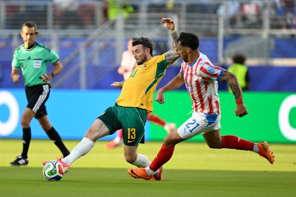 Australia’s Aiden O’Neill (13) battles for the ball with Paraguay’s Gabriel Avalos (21).