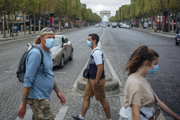 People wearing face masks cross the Champs-Elysees in Paris.