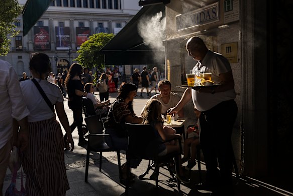 A waiter works at a terrace bar with water-sprayers in Madrid.