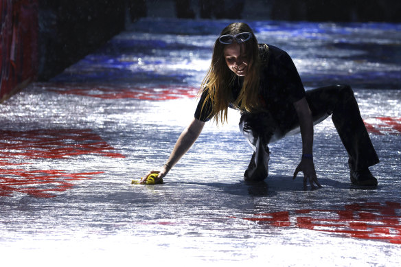 A worker attempts to dry the runway during steady rain before the Tommy Hilfiger show.