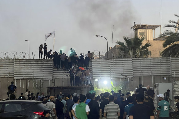 Protesters scale a wall at the Swedish embassy in Baghdad.