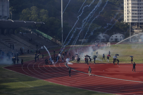 Students try to clear the tear gas canisters fired by riot police on the sports track during a confrontation in the Chinese University in Hong Kong.