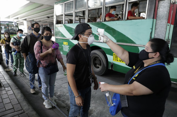 People have their temperatures checked before boarding a bus in Manila. Traffic jams and crowds of commuters returned to the streets on Monday as The Philippines started to reopen the economy.