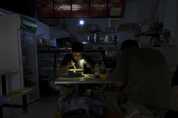 A man uses his smartphone to light up his breakfast during a blackout in Shenyang in north-eastern China.