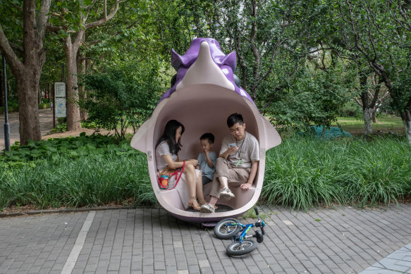 A boy sits with his parents in a park in Beijing.