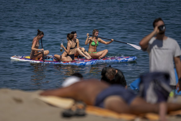 Women cool off as they paddle on a hot and sunny day at the beach in Barcelona.