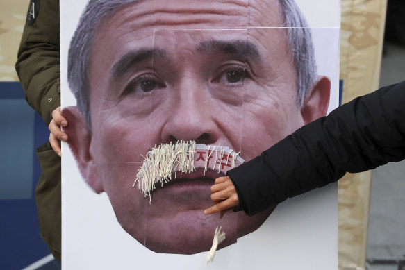 A protester plucks a fake moustache from a picture of the US ambassador to South Korea, Harry Harris.