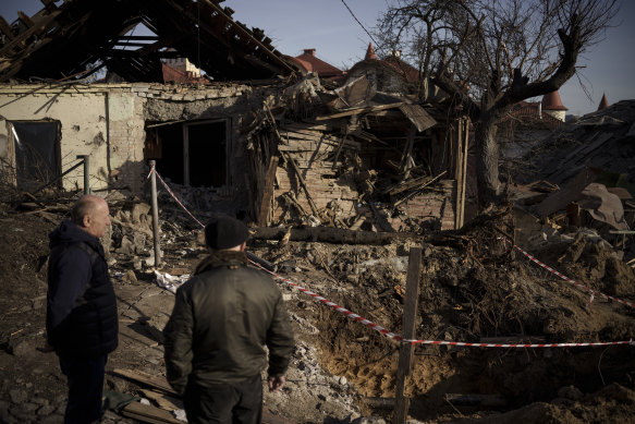 People stand next to the site of a Russian attack in Kyiv.