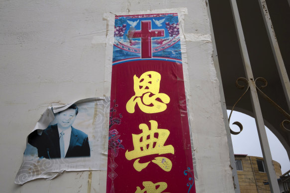 Resmi olmayan bir kilisenin dışındaki bir Hıristiyan posterinin yanında Çin Devlet Başkanı Xi Jinping'in solmuş bir fotoğrafı görülüyor.