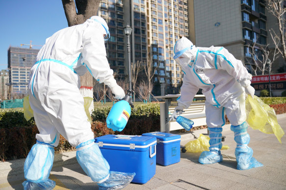 Workers disinfect containers of coronavirus test samples outside a residential complex in Shijiazhuang in northern China's Hebei Province on Friday.