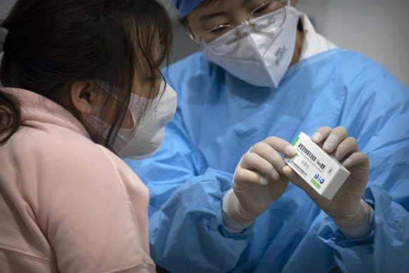 A medical worker shows a person the packaging for a Sinopharm vaccine at a vaccination facility in Beijing. Some countries have seen a rise in COVID cases after two doses of the vaccine and are recommending a third shot of a different vaccine.