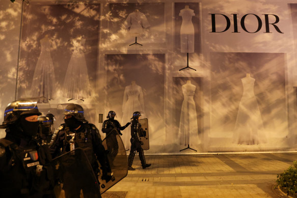 Police officers stand guard in front of the Dior building during riots at the Champs-Elysees in Paris on July 1.