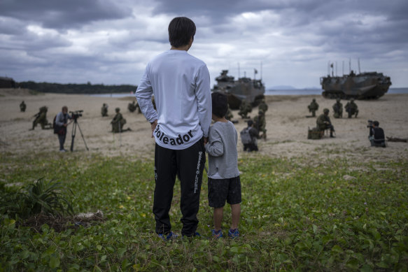 Tatsuya Shimobaba and his son, Eito, watch an amphibious landing exercise in Tokunoshima. A shrinking, agding population in Japan poses an obstacle as the nation tries to counter security threats from China and North Korea.