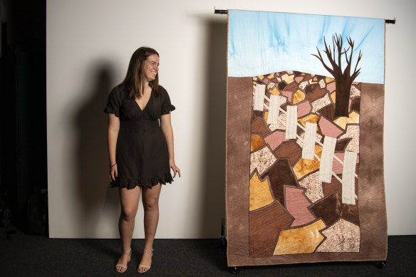 Kaitlyn McMahon with her major work, a quilt inspired by the NSW drought. She used elements from the landscape, including hessian and corn, to make it. 